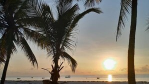 A beach with palm trees and the sun setting over the ocean. - Samara Studio Beachfront Apartment - Diani Beach (Diani Beach)