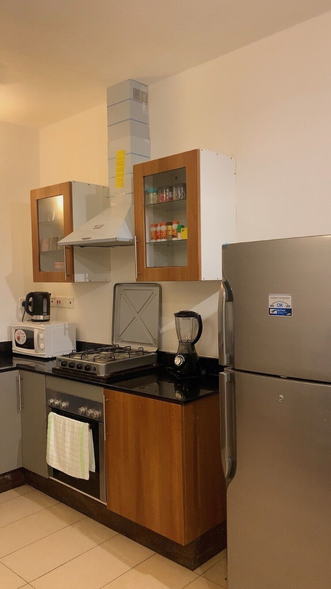 A compact kitchen with a stove, microwave, toaster, and a refrigerator.
