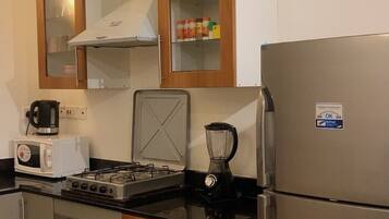 A compact kitchen with a stove, microwave, toaster, and a refrigerator.