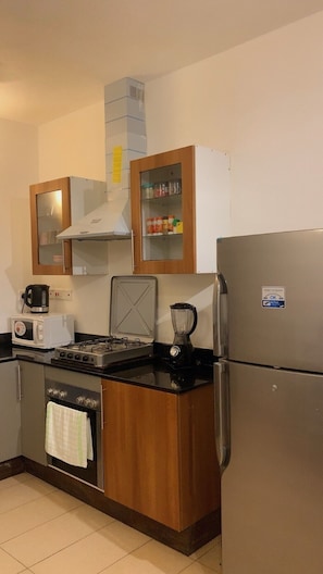 Eine kompakte Küche mit Herd, Mikrowelle, Toaster und Kühlschrank.