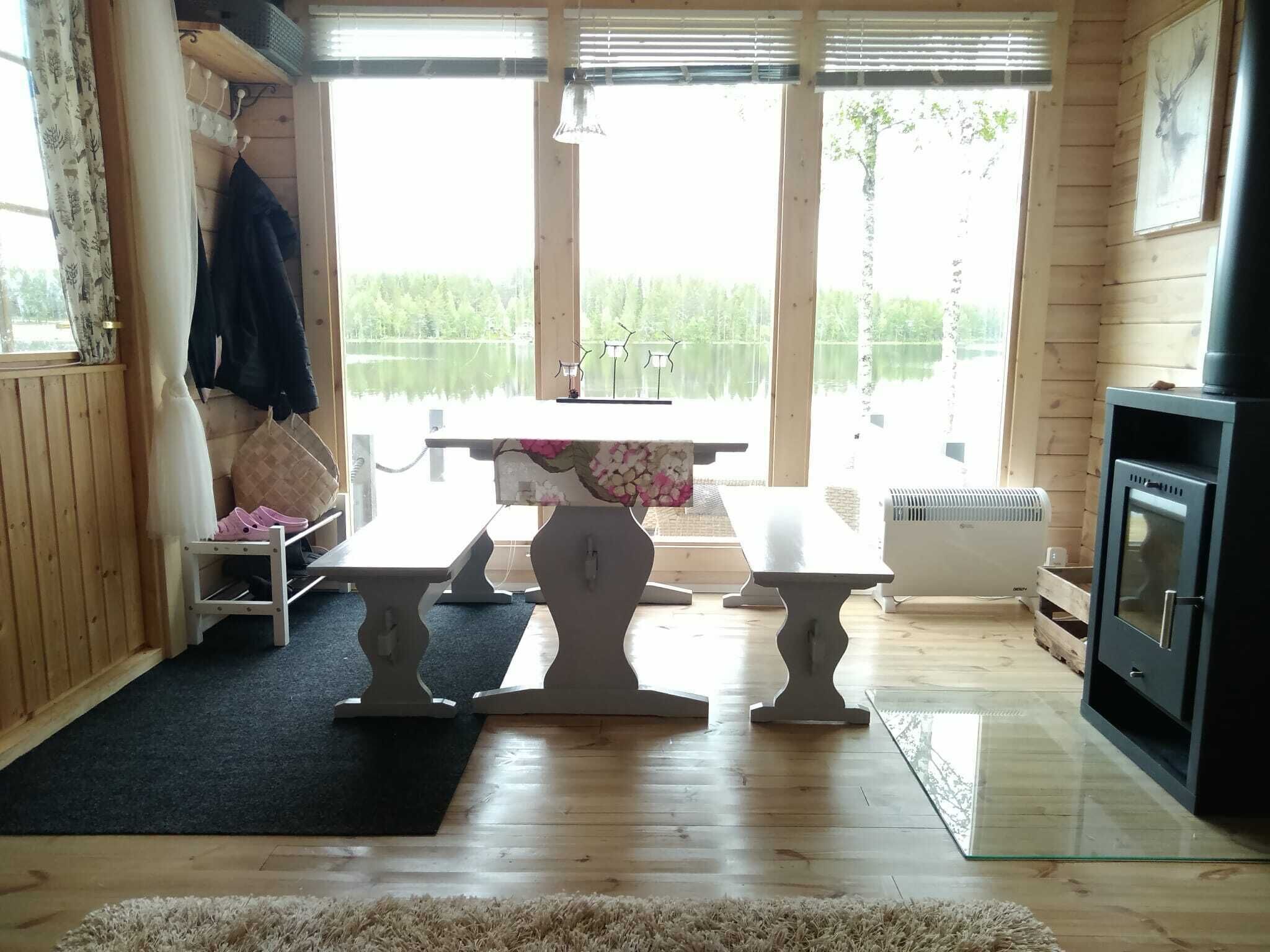 Un intérieur en bois avec une table et des bancs, une cheminée et une vue sur un lac.