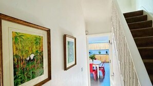 Ein Flur mit einer Treppe, Holzböden und gerahmten Kunstwerken an den Wänden.