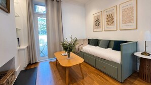 Ein modernes Zimmer mit einer Couch, einem kleinen Tisch und einem Fenster mit Vorhängen.