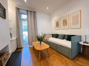 A modern room with a sofa, a small table, and a window with curtains. - Large family house 5 mins walk from station free parking (London)