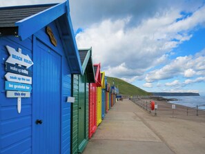 A row of colorful beach huts with directional signs and a coastal view. - A Georgian apartment in Mariner’s House, beside Little Pannett Park in Whitby. (Whitby)
