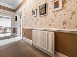 A hallway with patterned wallpaper, a radiator, and framed artwork on the wall. - A Georgian apartment in Mariner’s House, beside Little Pannett Park in Whitby. (Whitby)
