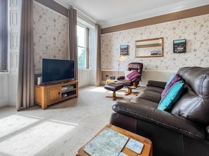 A living room with a leather sofa, a television on a wooden stand, and a patterned rug. - A Georgian apartment in Mariner’s House, beside Little Pannett Park in Whitby. (Whitby)