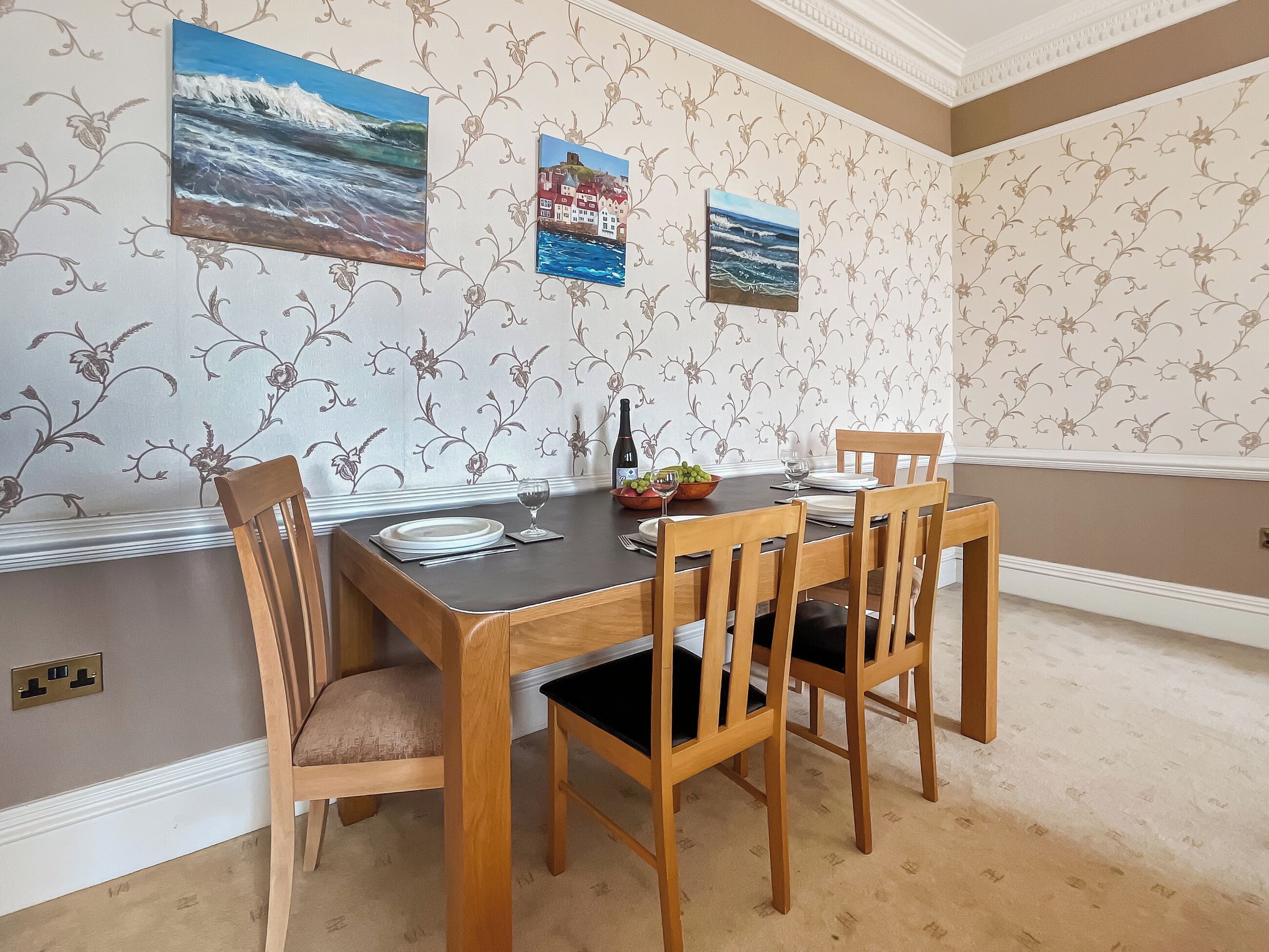 A dining area with a table set for four, surrounded by wooden chairs.