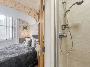 A hotel room with a bed, a shower, and a window with curtains. - A Georgian apartment in Mariner’s House, beside Little Pannett Park in Whitby. (Whitby)