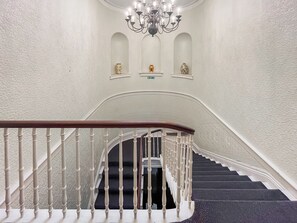 A grand staircase with white balusters, a dark carpeted landing, and a chandelier. - A Georgian apartment in Mariner’s House, beside Little Pannett Park in Whitby. (Whitby)