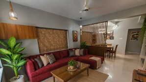 Uma sala de estar moderna com um sofá seccional vermelho, uma mesa de centro de madeira e uma área de jantar com uma mesa e cadeiras de madeira.