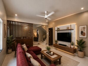 Una sala de estar moderna con un sofá rojo, una mesa de centro y un televisor montado en la pared.