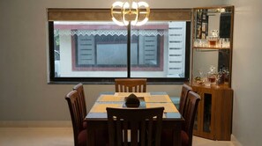Un comedor con una mesa y sillas, una ventana con vistas, y un aparador con cristalería.