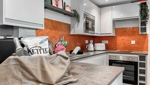 Een moderne keuken met witte kastjes, een magnetron, een broodrooster en een decoratief welkomstbord.