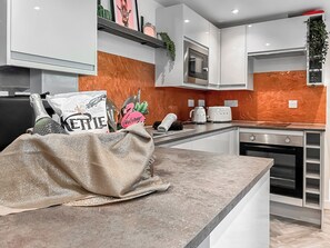 A modern kitchen with white cabinets, a microwave, a toaster, and a decorative welcome sign. - 1 bedroom accommodation in Stranraer (Stranraer)