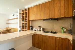 Eine moderne Küche mit Holzausstattung, einem Gasherd und einer Kaffeemaschine.