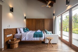 A modern bedroom with a wooden headboard, a bed with white bedding, a small round wooden table, and a balcony with a view. - Private 3BR Villa Uluwatu 5 Mins to Beach (Pecatu)
