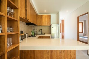 Cozinha moderna com armários de madeira, geladeira de aço inoxidável e bancada.