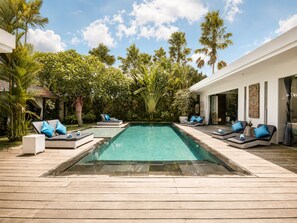 A pool area with lounge chairs and a wooden deck. - Rosa Paradise - Luxury 4BR Villa in Seminyak (Keroboken Kelod)