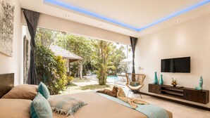 Ein modernes Schlafzimmer mit einem großen Bett, einem Fernseher und Blick auf ein Schwimmbad und einen Garten.