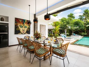 A dining area with a table set for six, surrounded by wicker chairs with teal cushions. - Rosa Paradise - Luxury 4BR Villa in Seminyak (Keroboken Kelod)