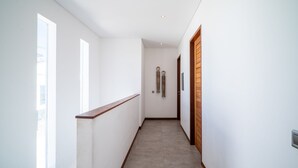 A narrow hallway with a wooden handrail on one side and a wooden door on the other. - Modern Coastal 4BR Villa Walk to Finns Canggu (Tibubeneng)
