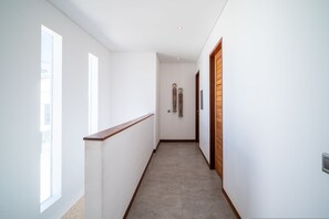 A narrow hallway with a wooden handrail on one side and a wooden door on the other. - Modern Coastal 4BR Villa Walk to Finns Canggu (Tibubeneng)