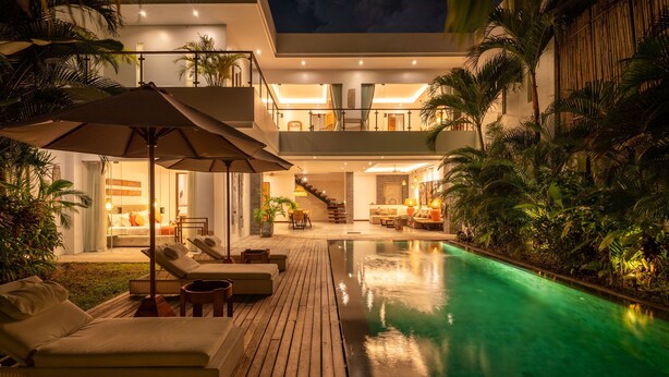 A modern outdoor pool area with a wooden deck, lounge chairs, and umbrellas. - Modern Coastal 4BR Villa Walk to Finns Canggu (Tibubeneng)