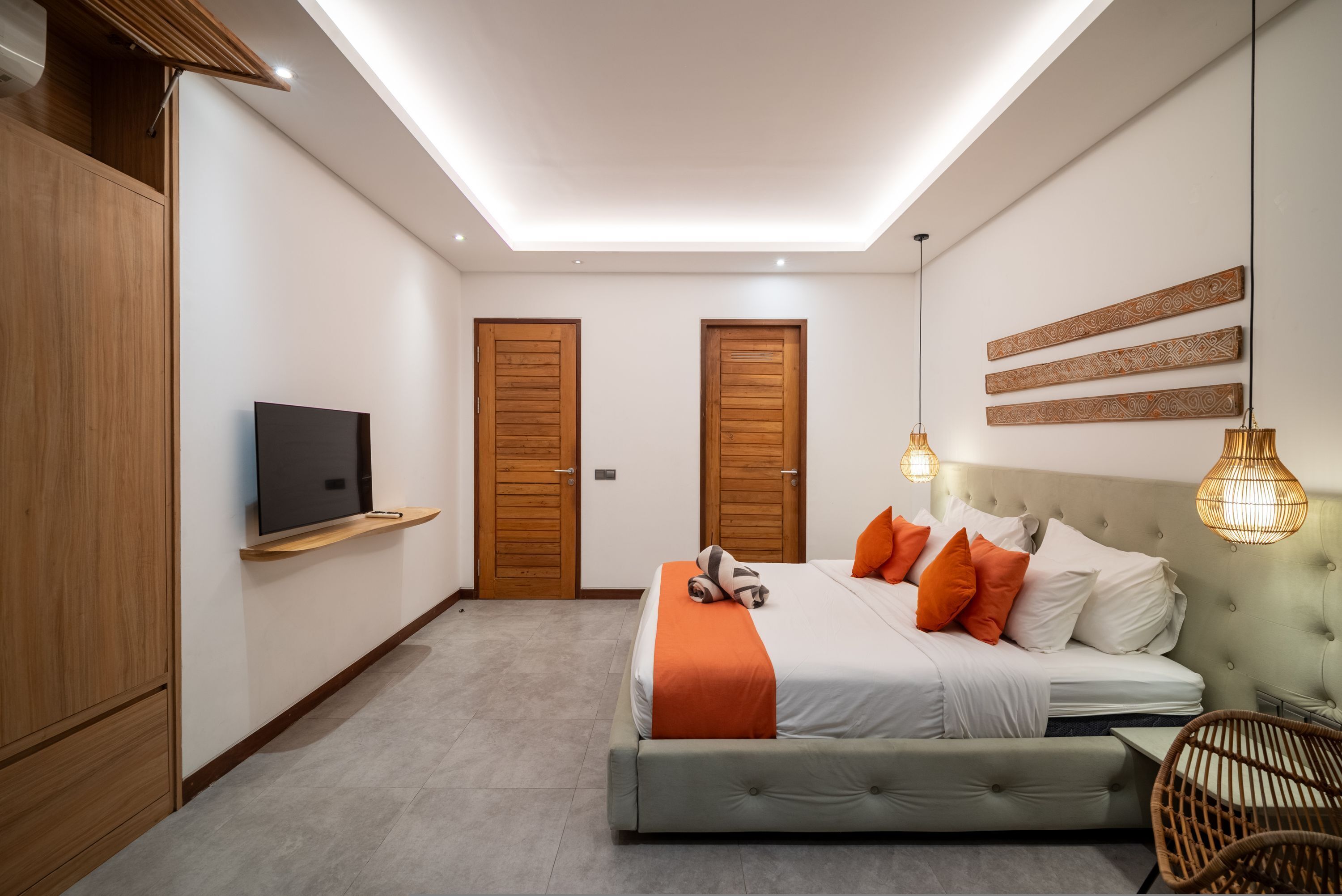 A modern bedroom with a bed, a television, and two doors.
