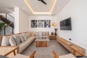 Ein modernes Wohnzimmer mit einer Eckcouch, einem Couchtisch und einem flachbildfernseher an der Wand.
