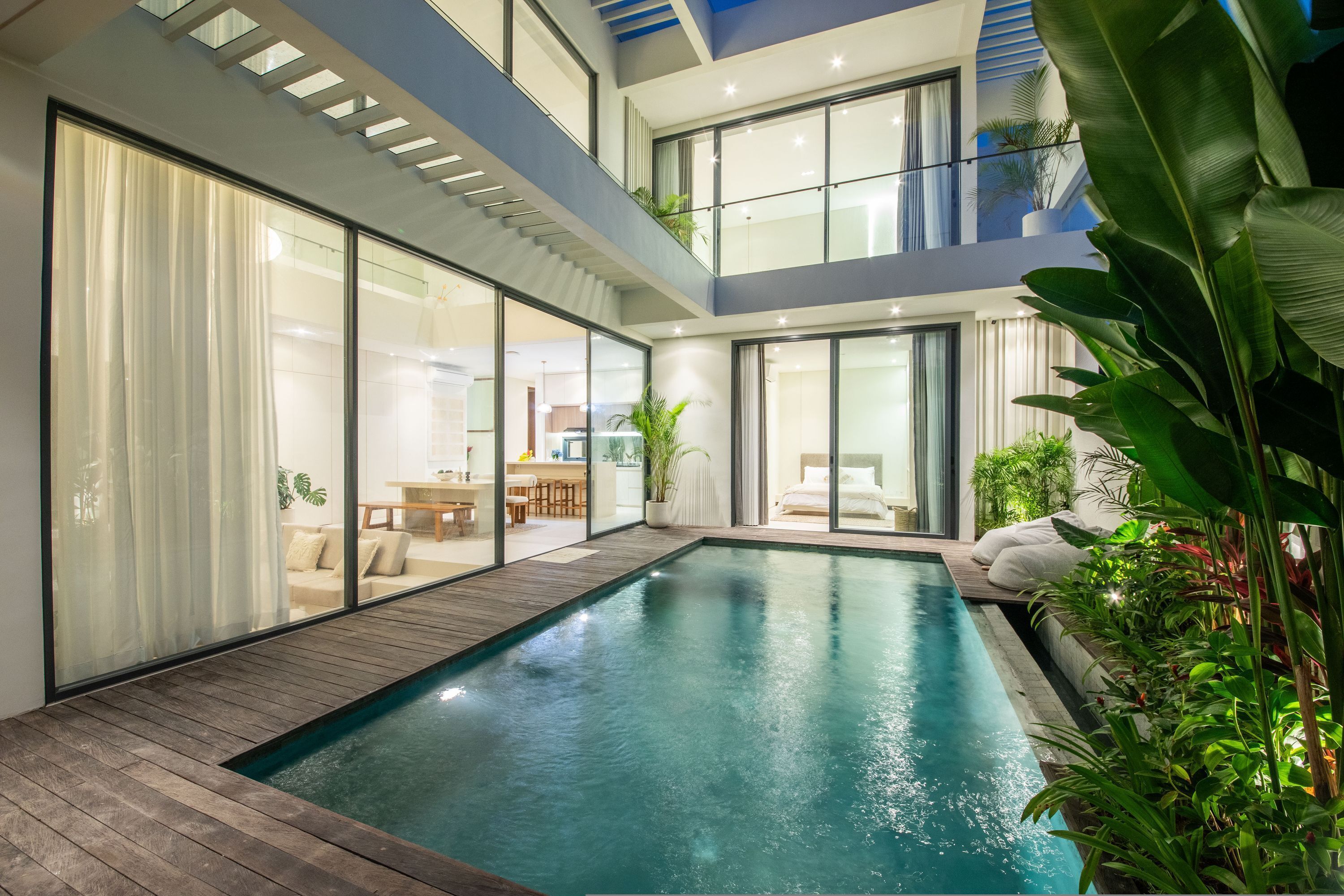 Una casa moderna con piscina, amplios ventanales y terraza de madera.