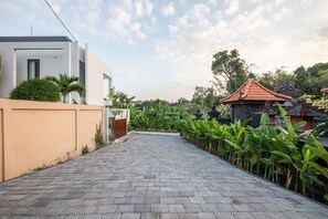 A paved pathway leading to a modern house with a traditional temple in the background. - Casa Rio-beautiful 3br Villa Center Seminyak (Keroboken Kelod)