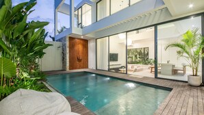 A modern house with a swimming pool, a patio with outdoor furniture, and a large glass door leading to an interior space. - Casa Rio-beautiful 3br Villa Center Seminyak (Keroboken Kelod)