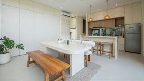 A modern kitchen with a central island, wooden bench, and a built-in refrigerator. - Casa Rio-beautiful 3br Villa Center Seminyak (Keroboken Kelod)