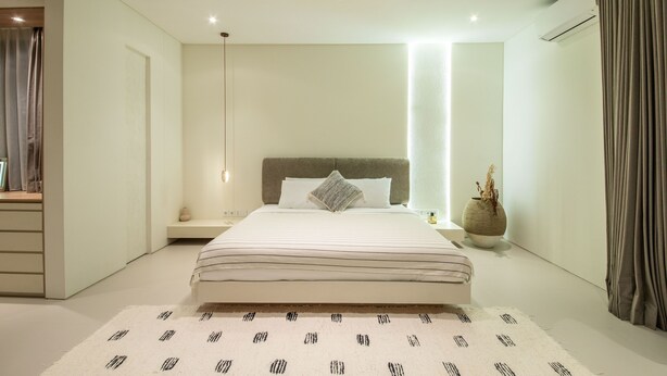 A modern bedroom with a large bed, bedside tables, a nightstand, and a decorative vase. - Casa Rio-beautiful 3br Villa Center Seminyak (Keroboken Kelod)
