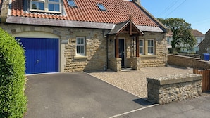 A stone cottage with a blue door, a small porch, and a tiled roof. - 3 bedroom accommodation in Beadnell (Beadnell)