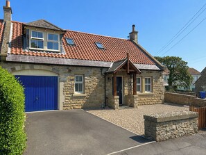A stone cottage with a blue door, a small porch, and a tiled roof. - 3 bedroom accommodation in Beadnell (Beadnell)
