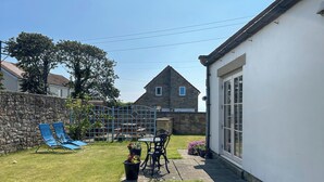 A backyard with a stone wall, a blue slide, a table with chairs, and a house with a stone facade. - 3 bedroom accommodation in Beadnell (Beadnell)