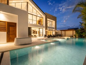 Ein modernes Haus mit Swimmingpool, Sitzgelegenheit im Freien und einer Treppe, die zu der oberen Etage führt.