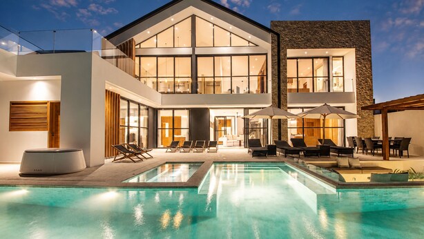A modern house with a large pool, outdoor seating, and a well-lit interior. - Modern 4 BR Villa Ocean View Nusa Dua (Nusa Dua)