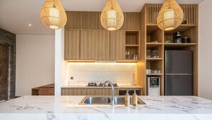A modern kitchen with a marble countertop, wooden cabinets, and a built-in stove. - Modern 4br Villa Canggu Rice View AC (Tibubeneng)