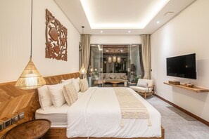 Ein modernes Schlafzimmer mit einem großen Bett, Nachttischen, einem Fernseher und einer Sitzecke mit einer Couch und Sesseln.