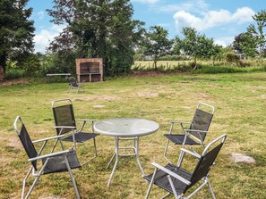 Een gazon met een ronde metalen tafel en vier opklapbare stoelen.