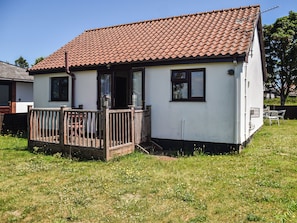 A single-story house with a tiled roof, a wooden deck, and a grassy yard. - 2 bedroom accommodation in Repps-with-Bastwick (Repps-with-Bastwick)