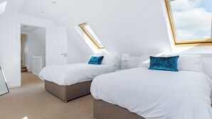 Ein modernes Schlafzimmer mit zwei Betten, einem Oberlicht und einem großen Fenster.