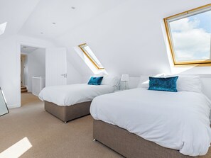 Ein modernes Schlafzimmer mit zwei Betten, einem Oberlicht und einem großen Fenster.