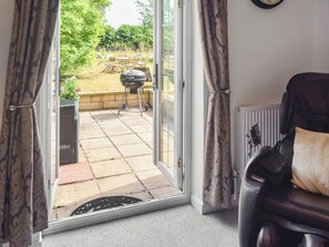 A room with a sliding glass door leading to an outdoor area with a barbecue grill. - 3 bedroom accommodation in Fleggburgh (Fleggburgh)