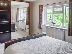 A bedroom with a bed, a wardrobe, a window with curtains, and a radiator. - 3 bedroom accommodation in Fleggburgh (Fleggburgh)