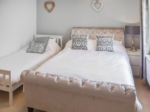 Una cama doble con cabecera capitonada, dos mesitas de noche con lámparas y adornos en forma de corazón en la pared.