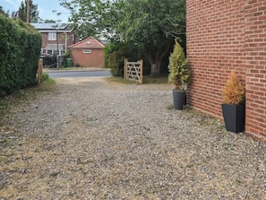 A gravel driveway leading to a brick house with a metal gate. - 3 bedroom accommodation in Fleggburgh (Fleggburgh)